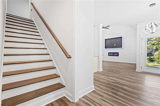 staircase featuring an inviting chandelier, baseboards, and wood finished floors