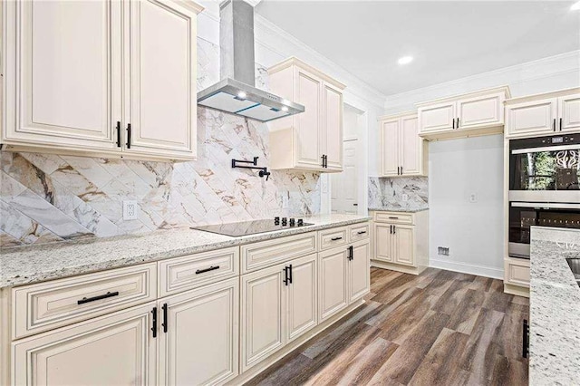 kitchen featuring crown molding, dark wood finished floors, double oven, wall chimney range hood, and black electric cooktop