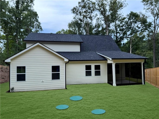 back of property featuring a sunroom, roof with shingles, fence, and a yard