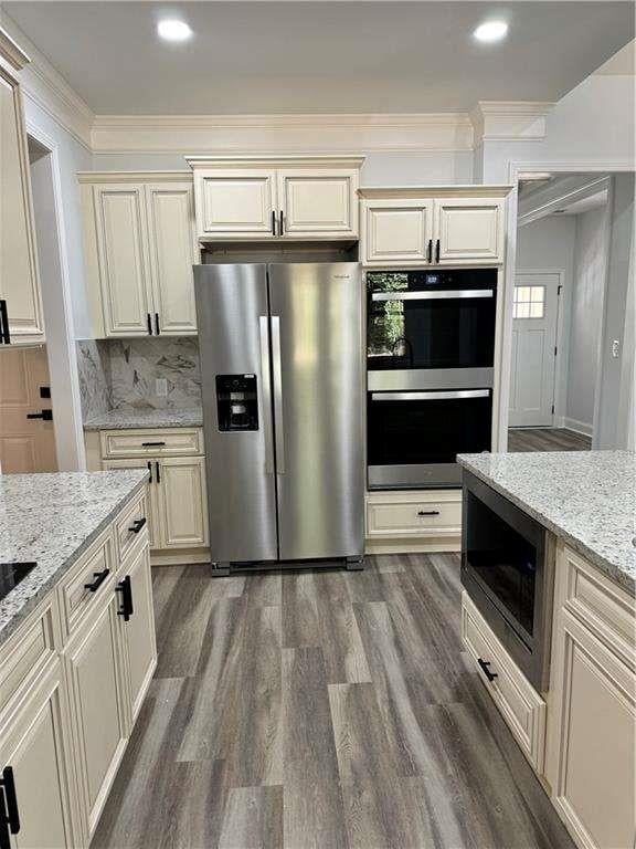 kitchen with appliances with stainless steel finishes, dark wood-type flooring, and ornamental molding