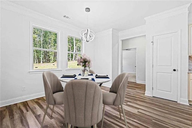 dining area with wood finished floors, visible vents, crown molding, and an inviting chandelier