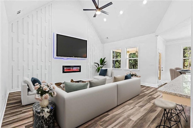 living room featuring visible vents, dark wood finished floors, a ceiling fan, a glass covered fireplace, and high vaulted ceiling