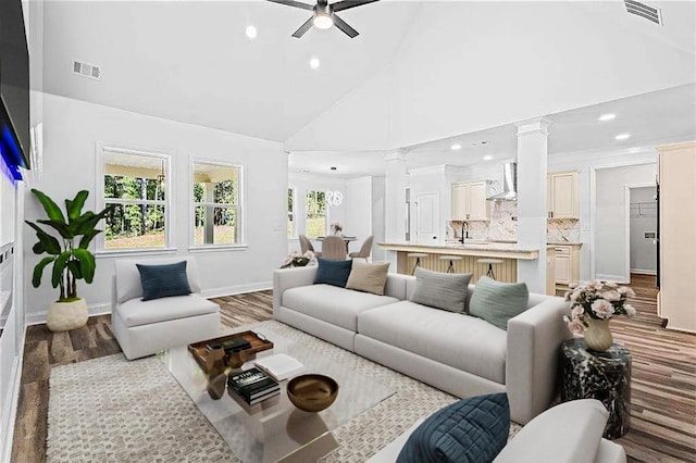 living room with high vaulted ceiling, visible vents, ceiling fan, and ornate columns