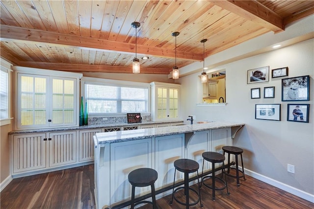 kitchen with wooden ceiling, a peninsula, a breakfast bar, dark wood-style flooring, and beam ceiling