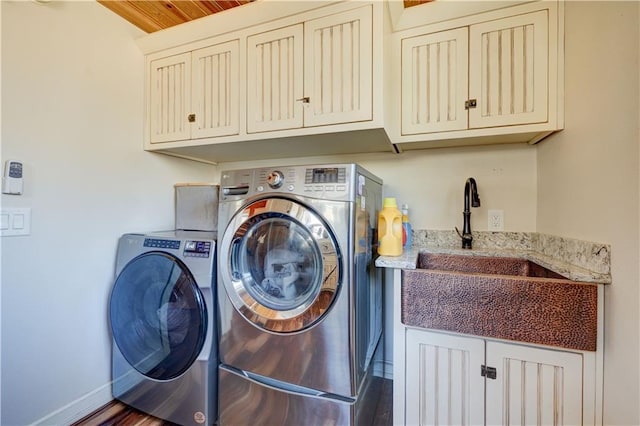 clothes washing area with cabinet space, a sink, washer and clothes dryer, and baseboards