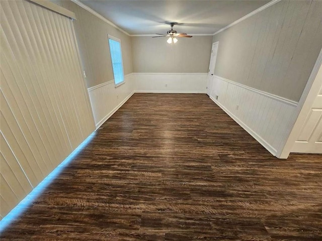 interior space with a ceiling fan, a wainscoted wall, dark wood-style floors, and crown molding
