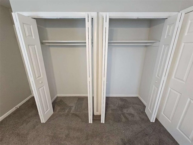 unfurnished room featuring baseboards, visible vents, and dark carpet