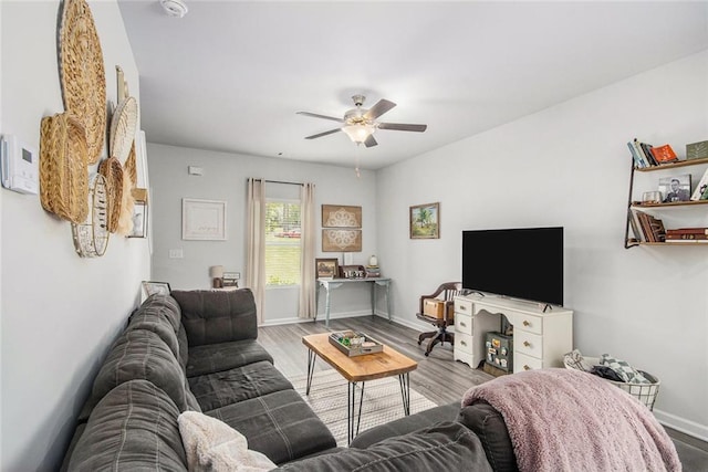 living room featuring ceiling fan, baseboards, and wood finished floors