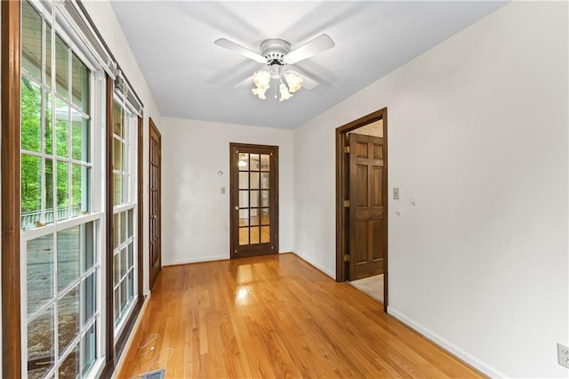 empty room with baseboards, light wood-type flooring, and ceiling fan
