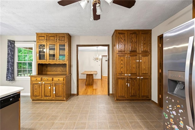 kitchen featuring stainless steel appliances, a textured ceiling, brown cabinetry, and baseboards