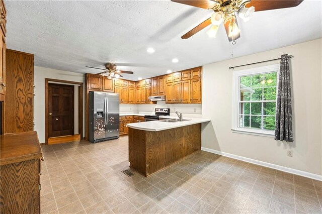 kitchen featuring appliances with stainless steel finishes, ceiling fan, a sink, a peninsula, and brown cabinets
