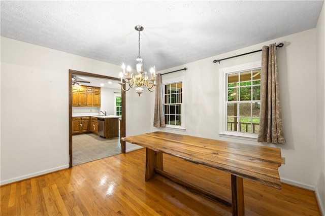 unfurnished dining area with a chandelier, baseboards, and light wood finished floors