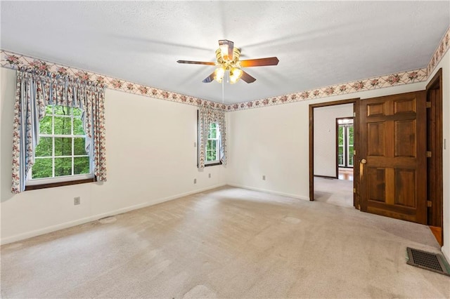 empty room featuring ceiling fan, healthy amount of natural light, carpet flooring, and a textured ceiling