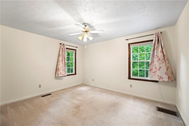 carpeted empty room featuring plenty of natural light, baseboards, ceiling fan, and a textured ceiling