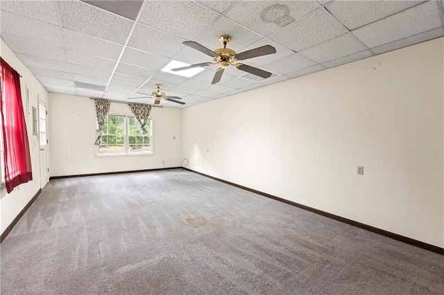 spare room with a paneled ceiling, carpet flooring, a ceiling fan, and baseboards