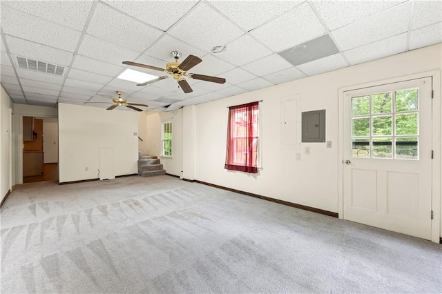 unfurnished living room with a paneled ceiling, electric panel, light colored carpet, stairway, and baseboards