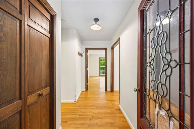 hallway featuring light wood finished floors and baseboards