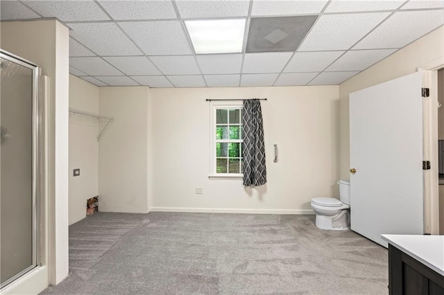 full bath featuring a stall shower, a drop ceiling, toilet, vanity, and baseboards