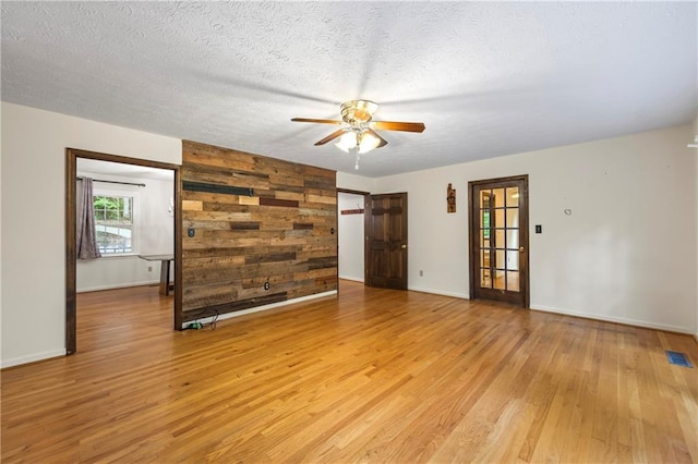 unfurnished room with ceiling fan, light wood-style flooring, baseboards, and a textured ceiling