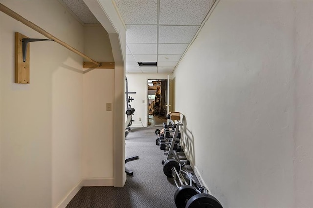 exercise area with a drop ceiling, baseboards, and carpet flooring