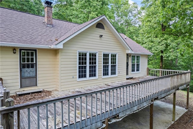 back of property with a chimney, a shingled roof, and a wooden deck