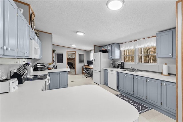 kitchen featuring white appliances, a peninsula, vaulted ceiling, light countertops, and a sink