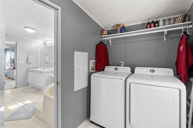 washroom with a textured ceiling, washing machine and dryer, laundry area, a sink, and electric panel