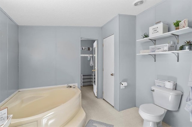 bathroom with toilet, a bath, and tile patterned floors