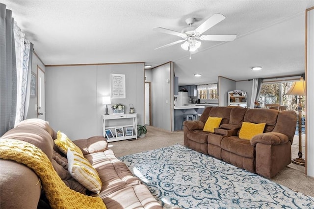 living area with a textured ceiling, a ceiling fan, and carpet flooring