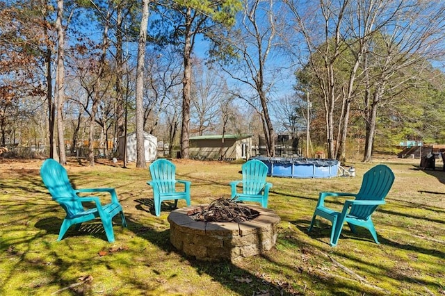 view of yard featuring an outdoor fire pit, a covered pool, an outdoor structure, and a storage unit