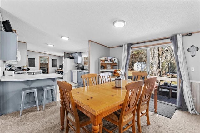 dining room with light colored carpet, crown molding, and a textured ceiling