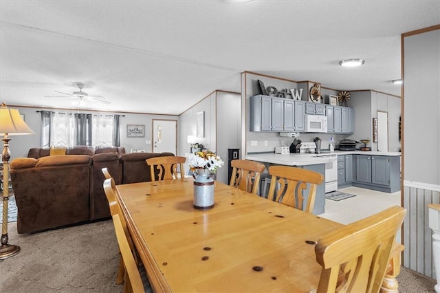 dining space featuring light carpet and ceiling fan