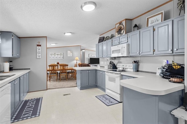 kitchen featuring gray cabinetry, a peninsula, white appliances, light countertops, and crown molding