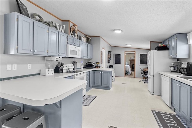 kitchen with white appliances, a peninsula, light countertops, crown molding, and light floors