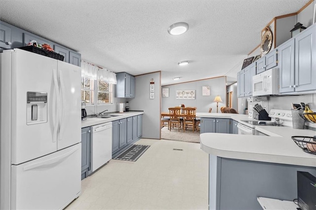 kitchen featuring light floors, light countertops, a sink, white appliances, and a peninsula