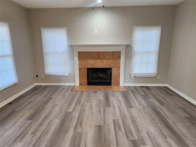 unfurnished living room featuring ceiling fan, light wood-type flooring, and a tiled fireplace