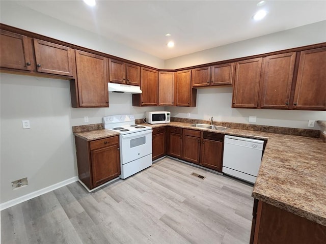 kitchen featuring dark stone countertops, sink, white appliances, and light wood-type flooring