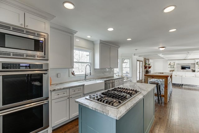 kitchen featuring backsplash, dark wood-type flooring, sink, a kitchen island, and stainless steel appliances