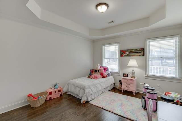 bedroom with dark hardwood / wood-style floors, a raised ceiling, ornamental molding, and multiple windows