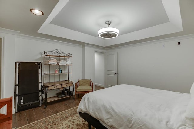 bedroom with a tray ceiling, dark hardwood / wood-style floors, and ornamental molding