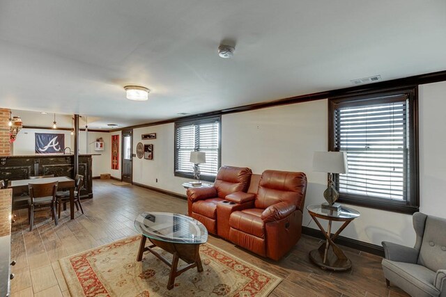 living room with hardwood / wood-style flooring, crown molding, and a healthy amount of sunlight