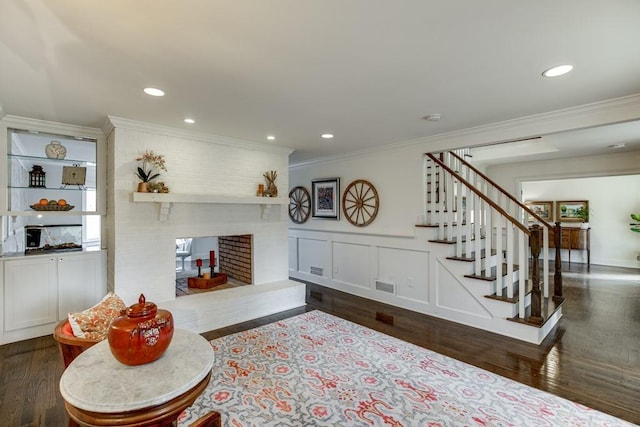 living room featuring ornamental molding, a fireplace, and dark wood-type flooring