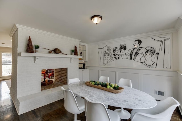 dining space with dark hardwood / wood-style flooring, ornamental molding, and a fireplace