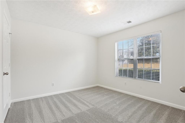 spare room featuring a textured ceiling and carpet