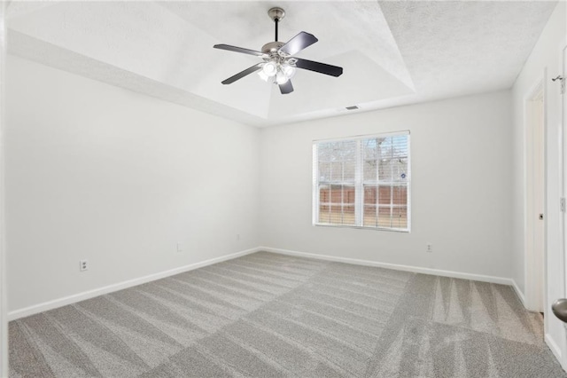 spare room featuring light colored carpet, ceiling fan, and a tray ceiling