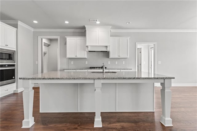 840 Champagne Ln, Hoschton, GA 30548 - kitchen featuring appliances with stainless steel finishes, light stone countertops, a kitchen island with sink, backsplash, and white cabinetry