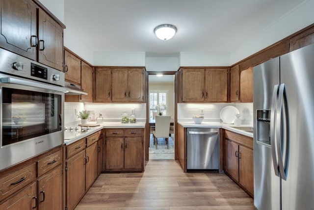 kitchen featuring stainless steel appliances, tasteful backsplash, and light hardwood / wood-style flooring