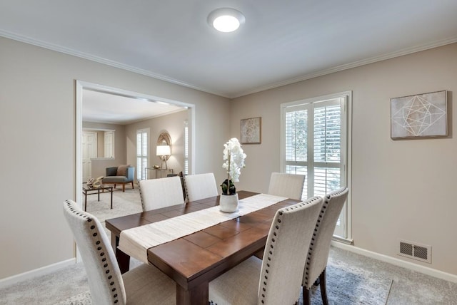 carpeted dining area with ornamental molding