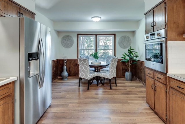 kitchen with stainless steel appliances, light hardwood / wood-style floors, and wood walls