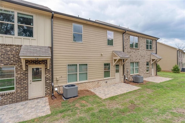 rear view of house featuring central AC unit, a yard, and a patio